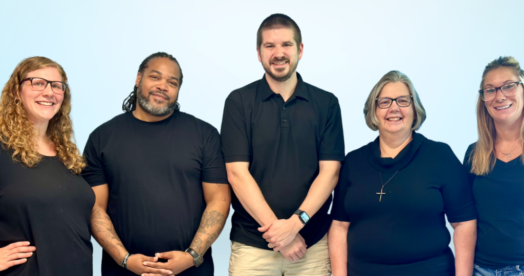 An image of our full team of staff - from left to right, Rachael (Office Manager), Charles (Recovery Director), Daniel (Senior Pastor), Jane (Associate Pastor), and Tasha (Custodian)